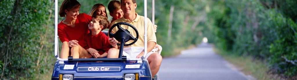 Family riding a blue golf cart down a shaded trail